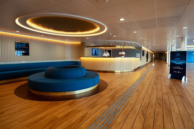 La salle de réception du nouveau ferry Moby Fantasy avec deux réceptionnistes et des assises pour faire patienter les voyageurs